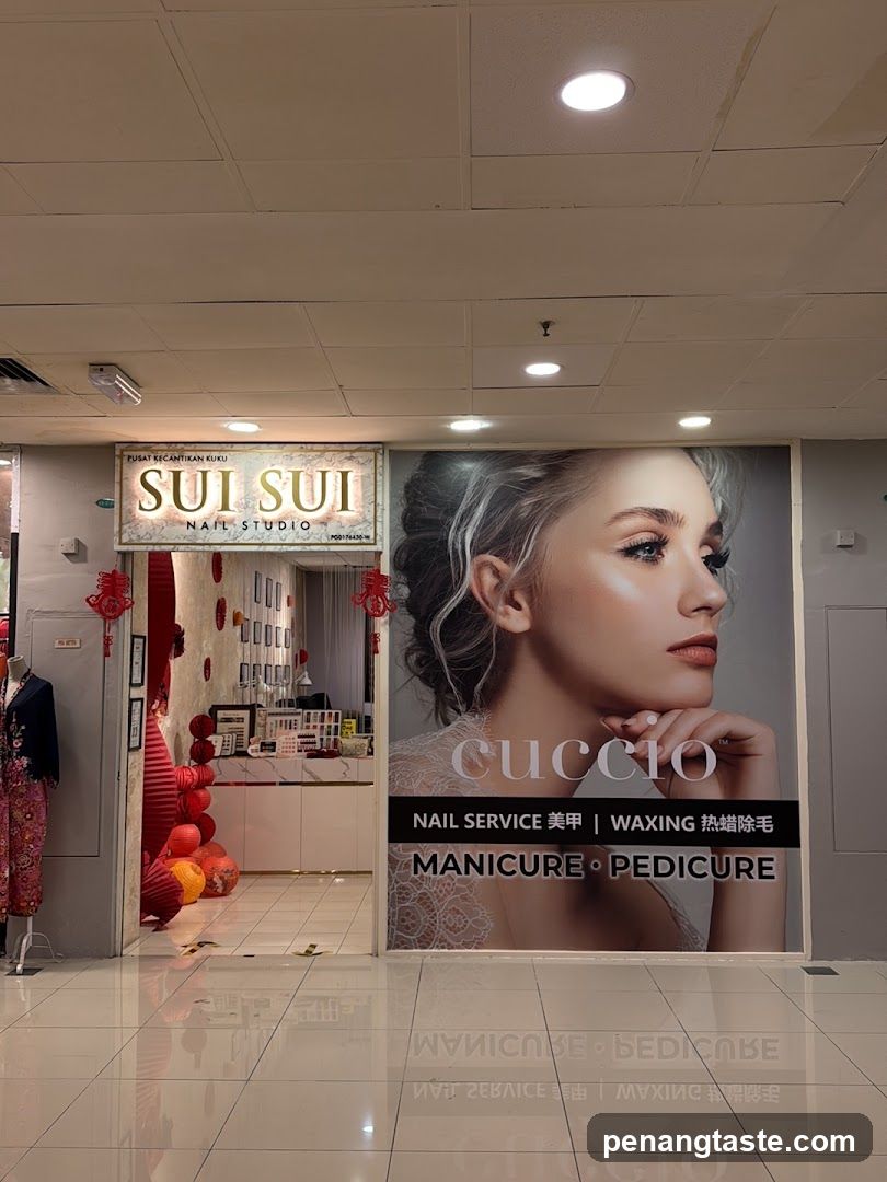 A storefront of a nail studio named 'Sui Sui' with visible signage above the entrance. The shop features red decorations and balloons inside, suggesting a festive or promotional event. A large poster on the wall advertises services like manicure, pedicure, waxing, and mentions the brand 'cuccio'. The interior is partially visible through the open doorway.