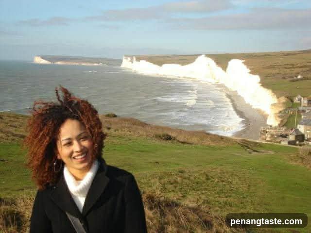 Woman on a coastal cliff with crashing waves in background