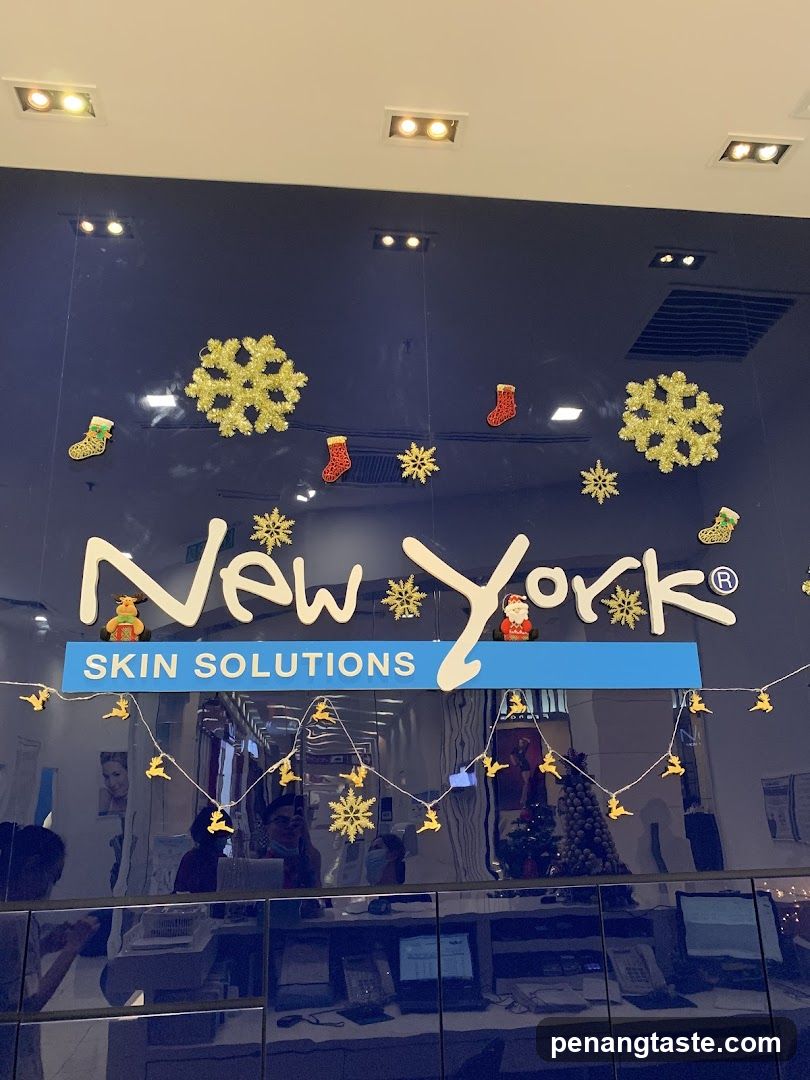 A storefront facade featuring a large sign reading 'New York' with 'SKIN SOLUTIONS' below in blue. Decorative elements include gold snowflakes, Christmas stockings, and reindeer garlands hanging above the entrance. The interior is partially visible through glass doors, showing desks, computers, and staff members working.