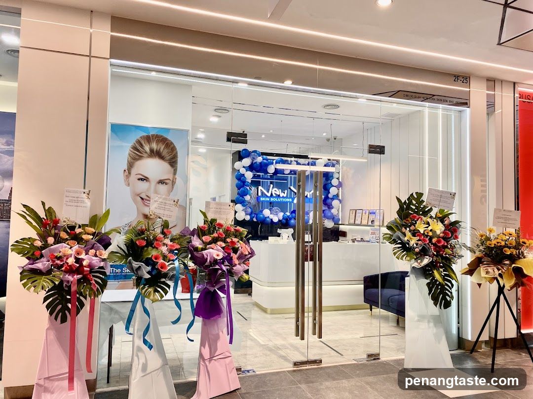 A modern glass storefront with floral bouquets and banners on either side, featuring a large poster of a smiling woman inside the shop.