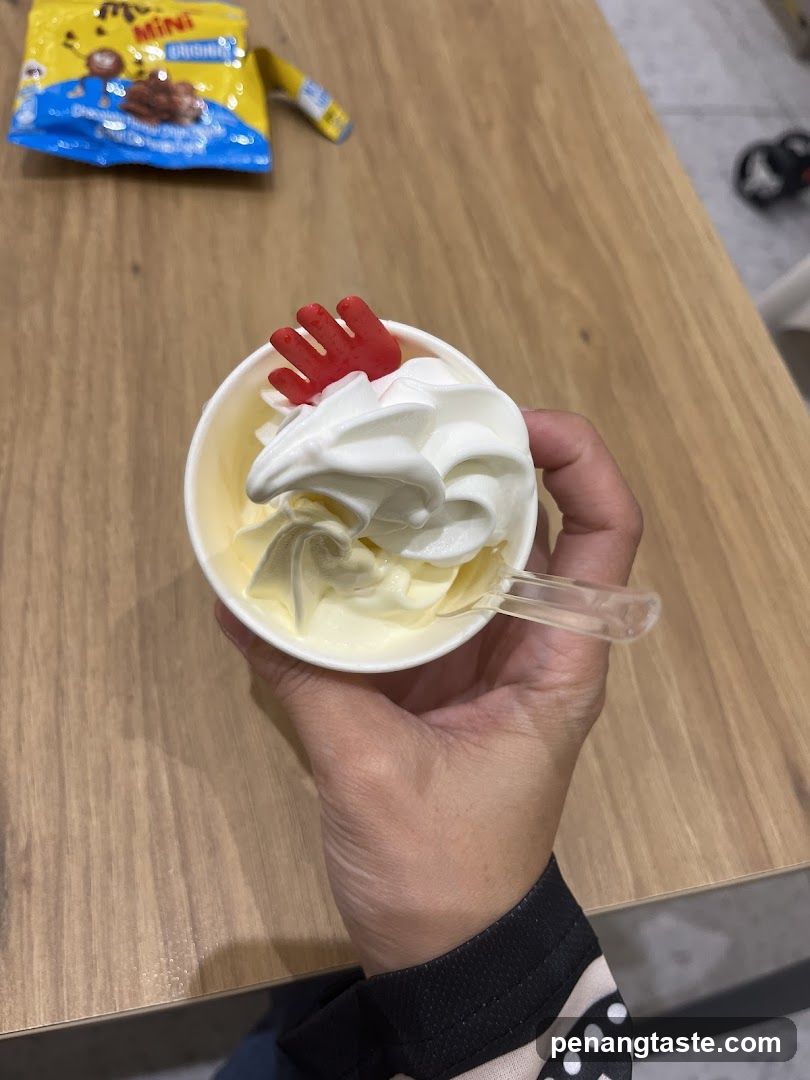 Hand holding a cup of ice cream with whipped cream and candy topping