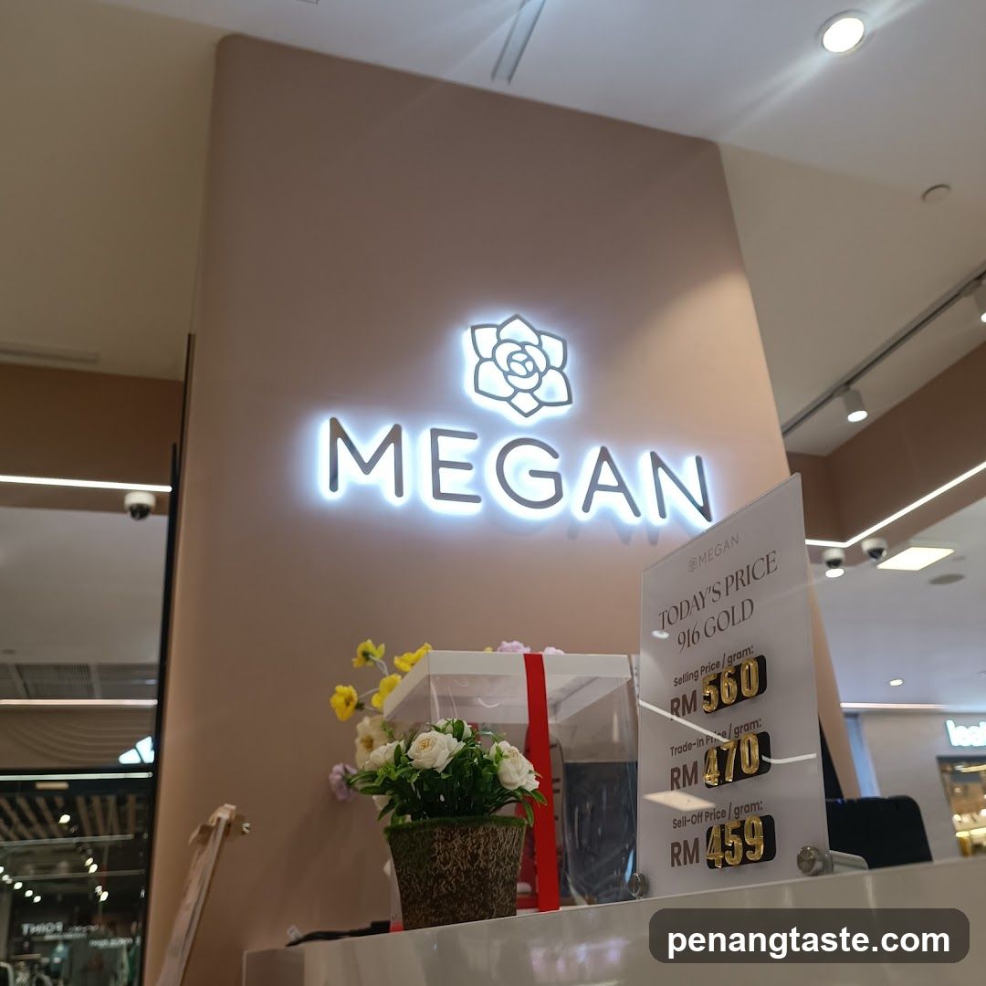 A photo of the Megan store entrance, featuring a lit sign with a flower logo and the word 'MEGAN' on a beige wall. A price display board shows today's gold prices in RM.